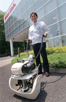 北條宏主任研究員とカセットガス式耕運機「ピアンタFV200」。ハンドルを折りたためば全高53cmとなり、ホンダ・インサイトなどセダンのトランクにも収まる大きさに。標準装備のカバーはストレスなく着脱できる。