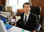 市長の椅子に座る竹原信一市長。1959年生まれ。83年防衛大学校卒、航空自衛隊に入隊。88年に退官してからは親族の経営する建設会社に勤務していた。社長を務めたこともある。