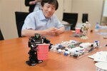 背丈が16.5cmのアイソボットに対し、紙コップは胸の高さ程度。ロボットの動く原理は、からくり人形とも共通点が。
