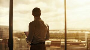 ビルの窓から見える夕焼けを眺める人