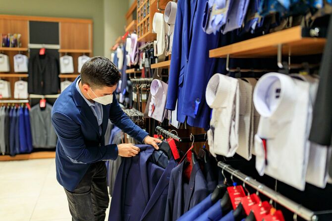 衣料品店でスーツを選ぶ男性