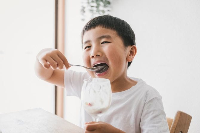 家でイチゴのパフェを食べる少年