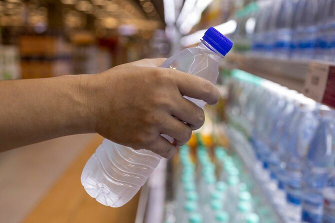 食料品店でボトル入り飲料水を買う男