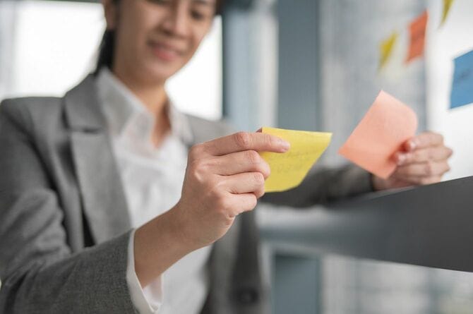 付箋の内容を見比べるビジネスウーマン
