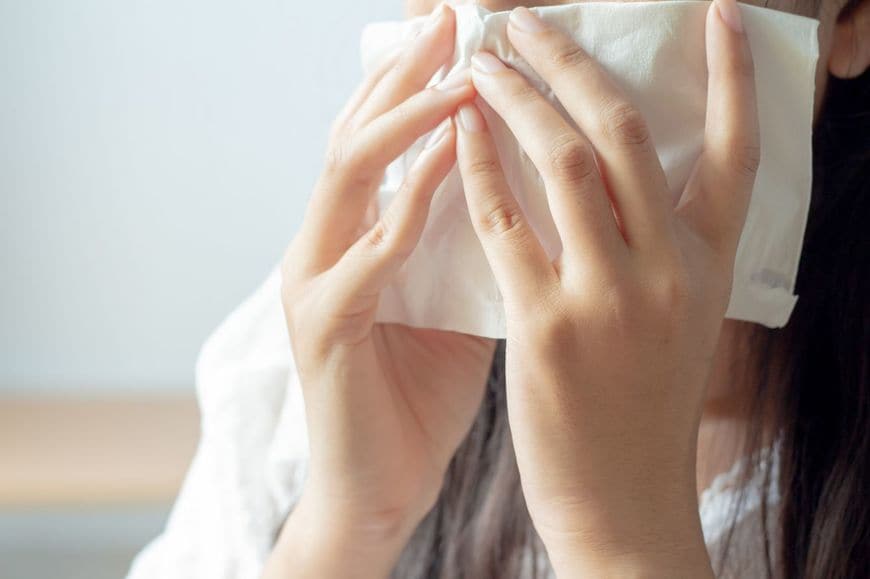 くしゃみをする女性のクローズアップ