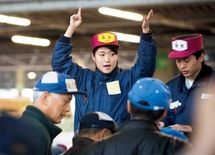 早朝の競り台で相場を仕切る女性販売人