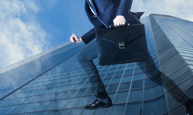走るビジネスマンと高層ビルのイメージ写真
