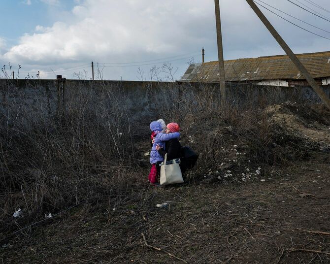 混乱する娘を落ち着かせるために人混みを離れ抱きしめる母親。ウクライナに国境を接するモルドバ共和国のパランカにて。