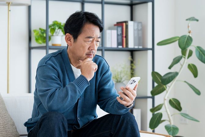 リビングでスマートフォンを使用する中年男性