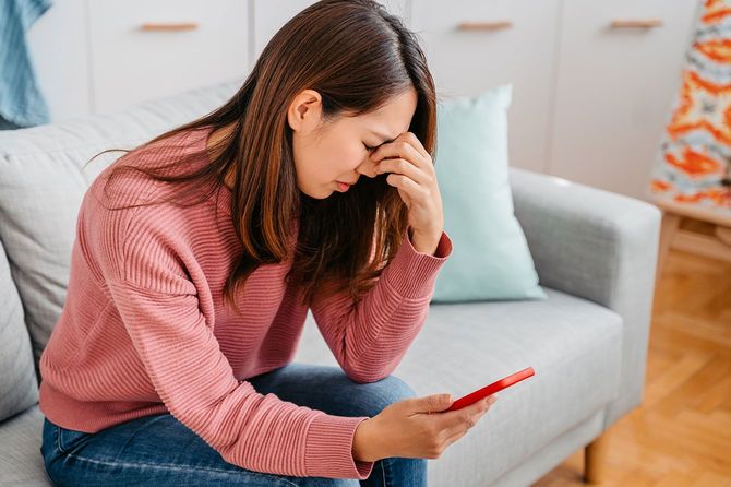 スマホを見て悲しむ女性