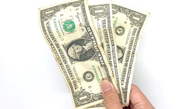 3ドル分の紙幣を持っている人の手