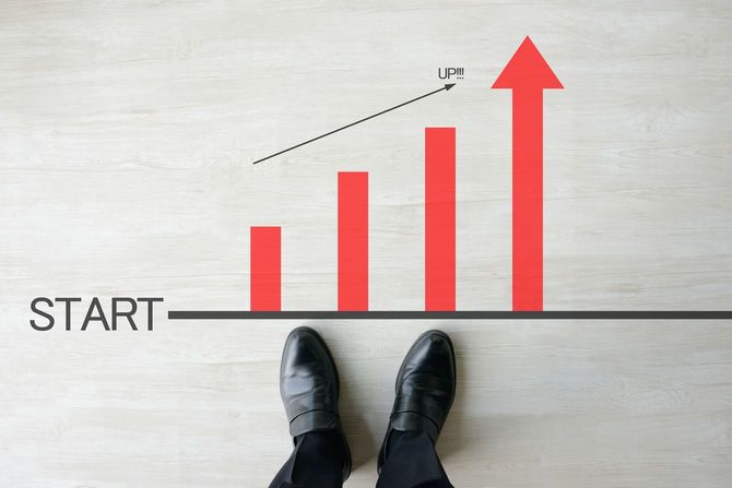 右肩上がりのグラフの前に立つ男性