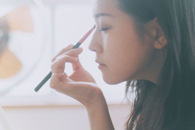 日本でまぶたにアイシャドウを塗る女性