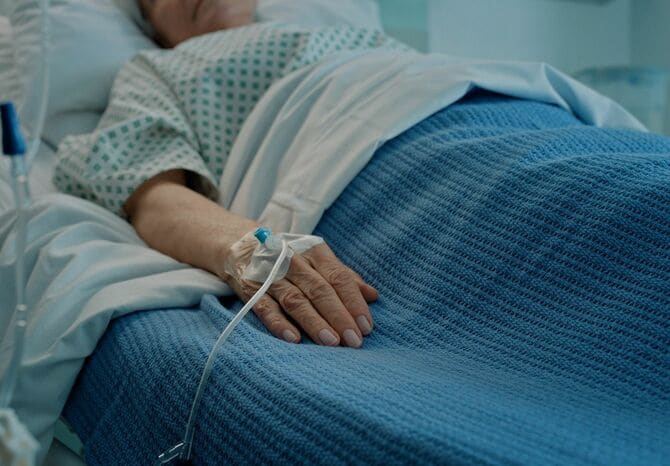 医療施設で点滴をつけてベッドに横たわる患者