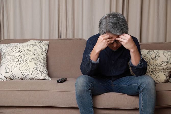 ソファに座ってうなだれる男性