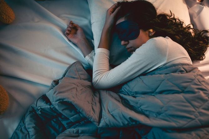 アイマスクと耳栓をつけて眠ろうとしている女性