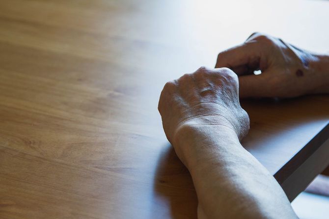 テーブルの上に手を置く老人