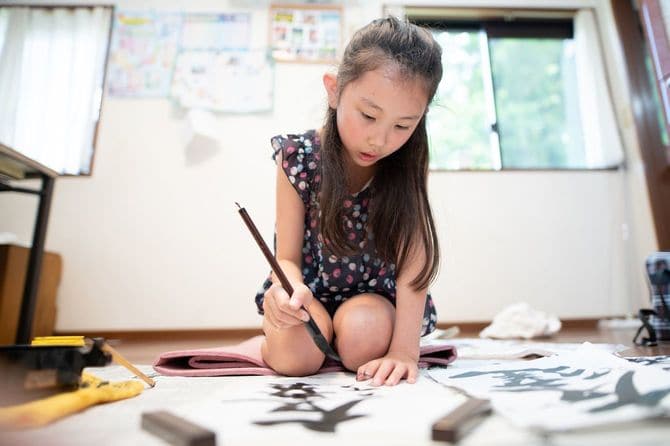 家で書き初めを書く子供