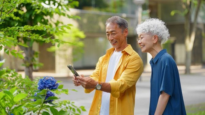 街で写真を撮るためにアジサイの花に立ち寄る年配のカップル