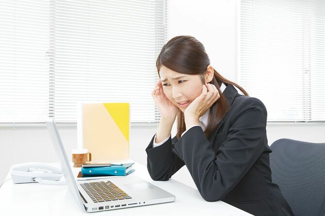 オフィスで困った顔でパソコン画面を見ている女性