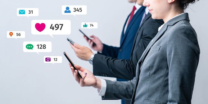 スマートフォンを持って並ぶ会社員とソーシャルメディアを表す吹き出し