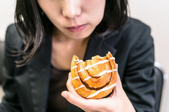 シナモンロールを食べるビジネスウーマン