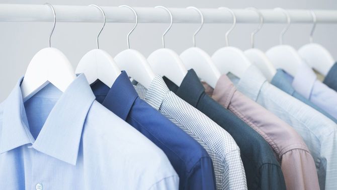 木製ハンガーに掛かっている各種の青いシャツ