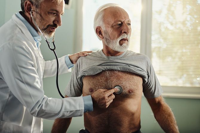 患者の胸に聴診器をあてる医師