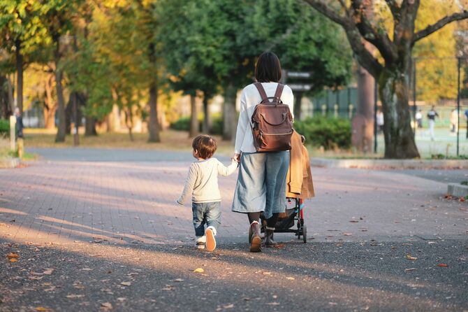 ベビーカーを押して歩く母親と手をつないで歩く男児