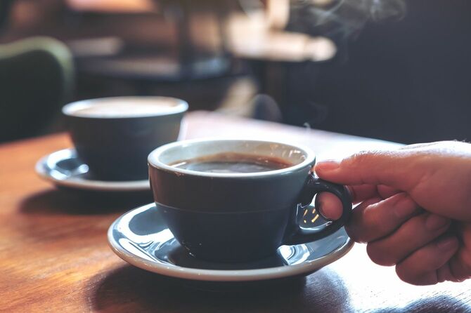 カフェでホットコーヒーのカップを持つ手元
