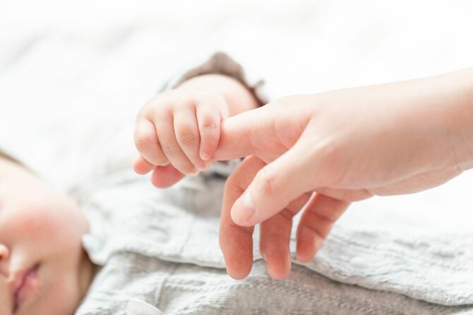 母親の指を握りしめる赤ちゃん