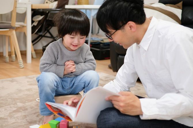 子どもに本を読んでいる楽しそうな父親