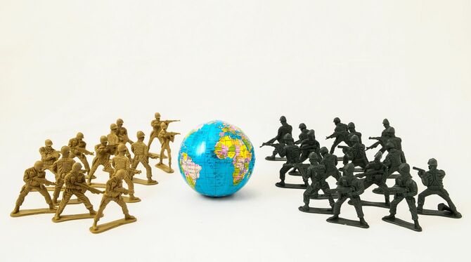 地球儀を挟んで銃を構えるおもちゃの兵隊たち