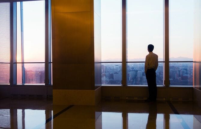 展望の開けたビルから街を見下ろしている男性
