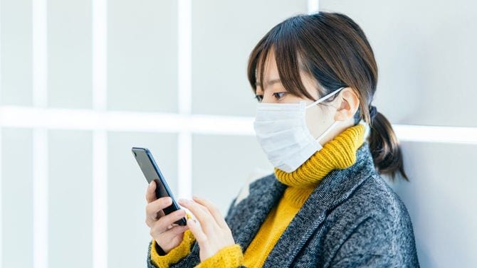 スマホを使用するマスクを着用した女性