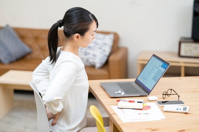 仕事中に腰の違和感を気にする女性