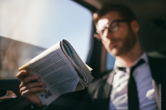 車の中でビジネスマンが新聞を読む
