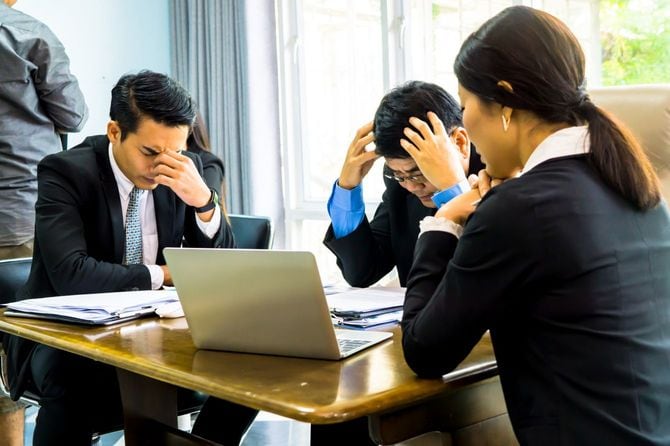 オフィスのテーブルに座っている落ち込んだビジネスパーソンたち