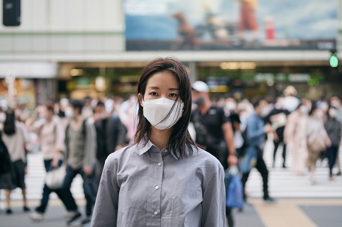 マスクを着けている女性、群衆もマスクを着用している