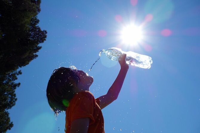 【写真】太陽の下でペットボトルの水を飲む子ども