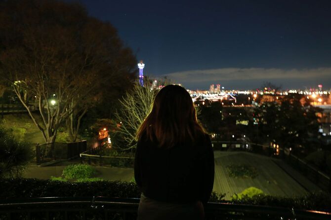 夜の公園で夜景を見ている女性の後ろ姿