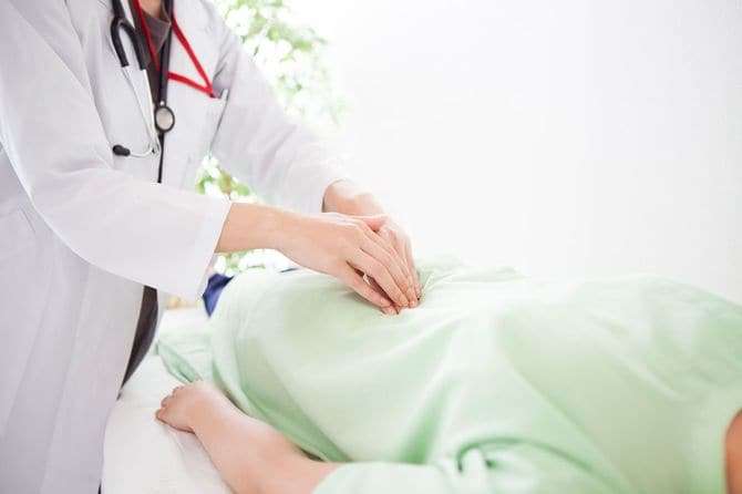 患者の腹部を触診する医師