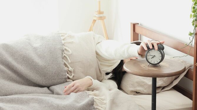 朝、目覚まし時計を消す女性
