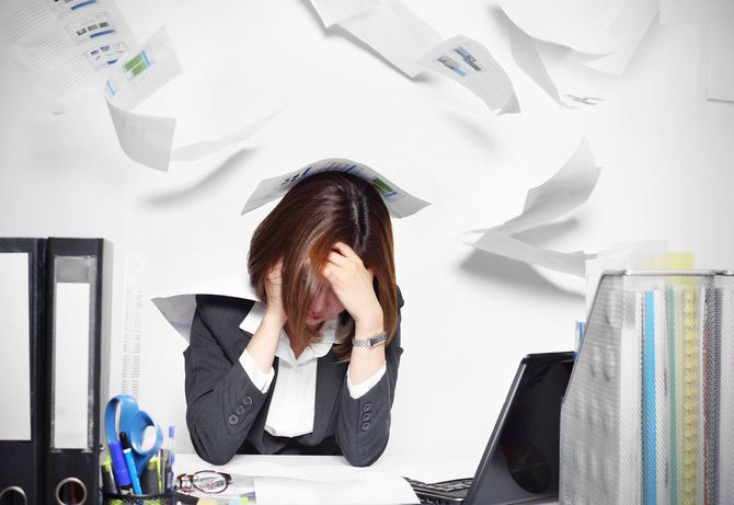 深刻そうな若い女性の頭の上を舞う大量の書類