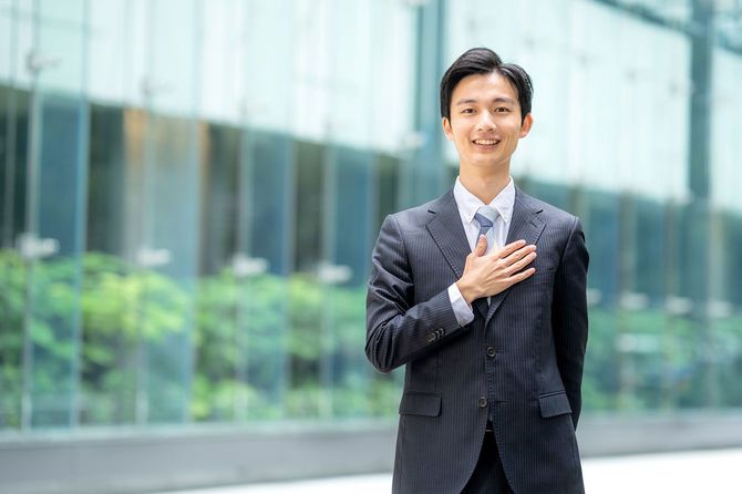 胸に手を当てて笑顔で立つビジネスマン