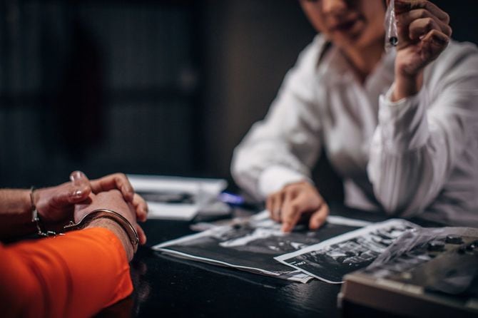 囚人の取り調べで証拠を見せる刑事の女性