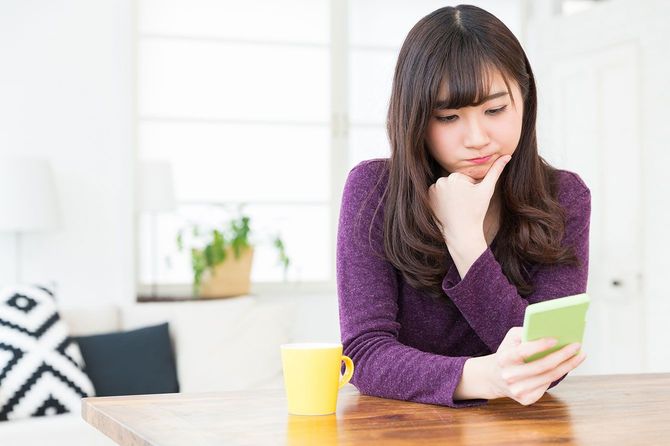 スマホを見ながら考え込む女性