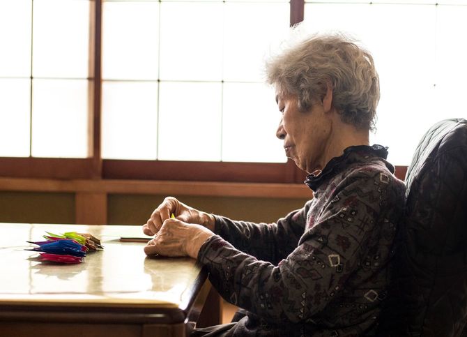 自宅で鶴を折るシニア女性