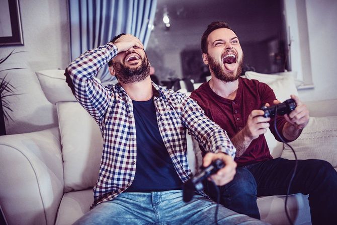 ソファに座ってテレビゲームをやる二人の男性