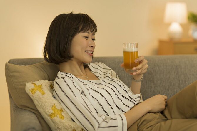 ソファでグラスを片手にくつろぐ女性